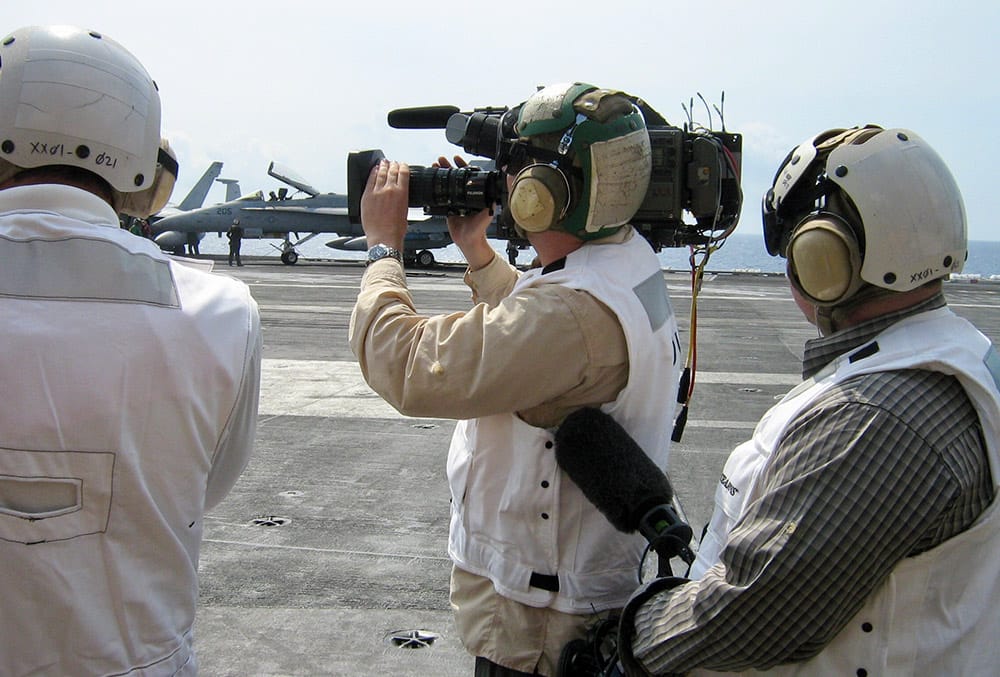 A man holding a camera on top of an airplane.