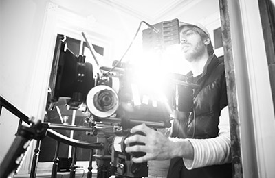 A man holding a camera in front of a large screen.