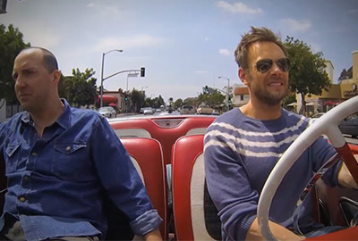 Two men riding a bus on the street.