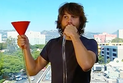 A man holding onto a red cup and drinking water