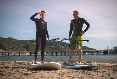 Two people standing on a beach with surf boards