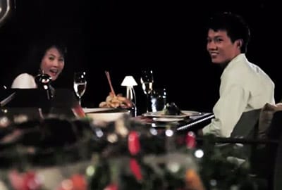 A man and woman sitting at a table with wine glasses.